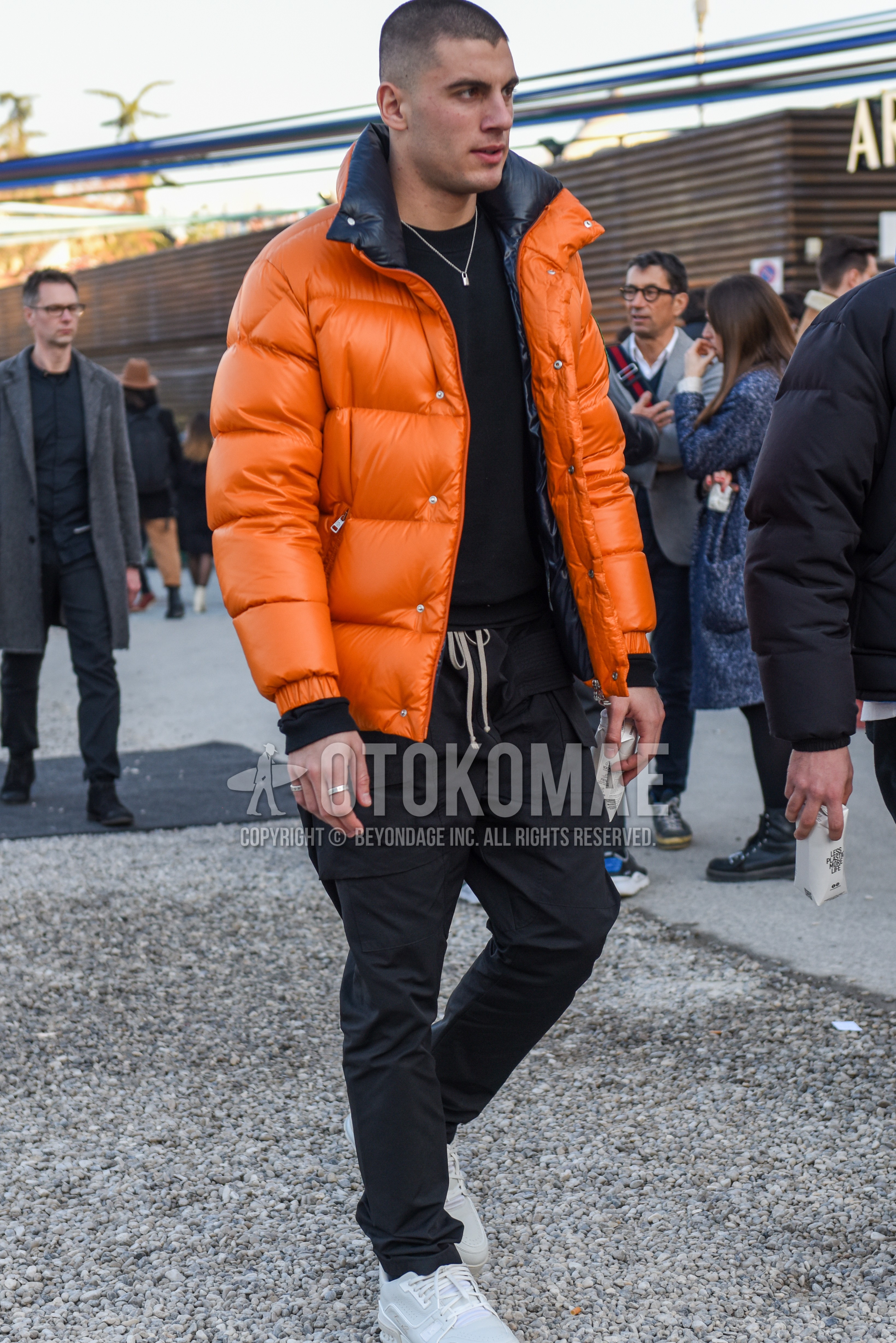 Men's autumn winter outfit with orange plain down jacket, black plain sweater, black plain easy pants, black plain cargo pants, white low-cut sneakers.