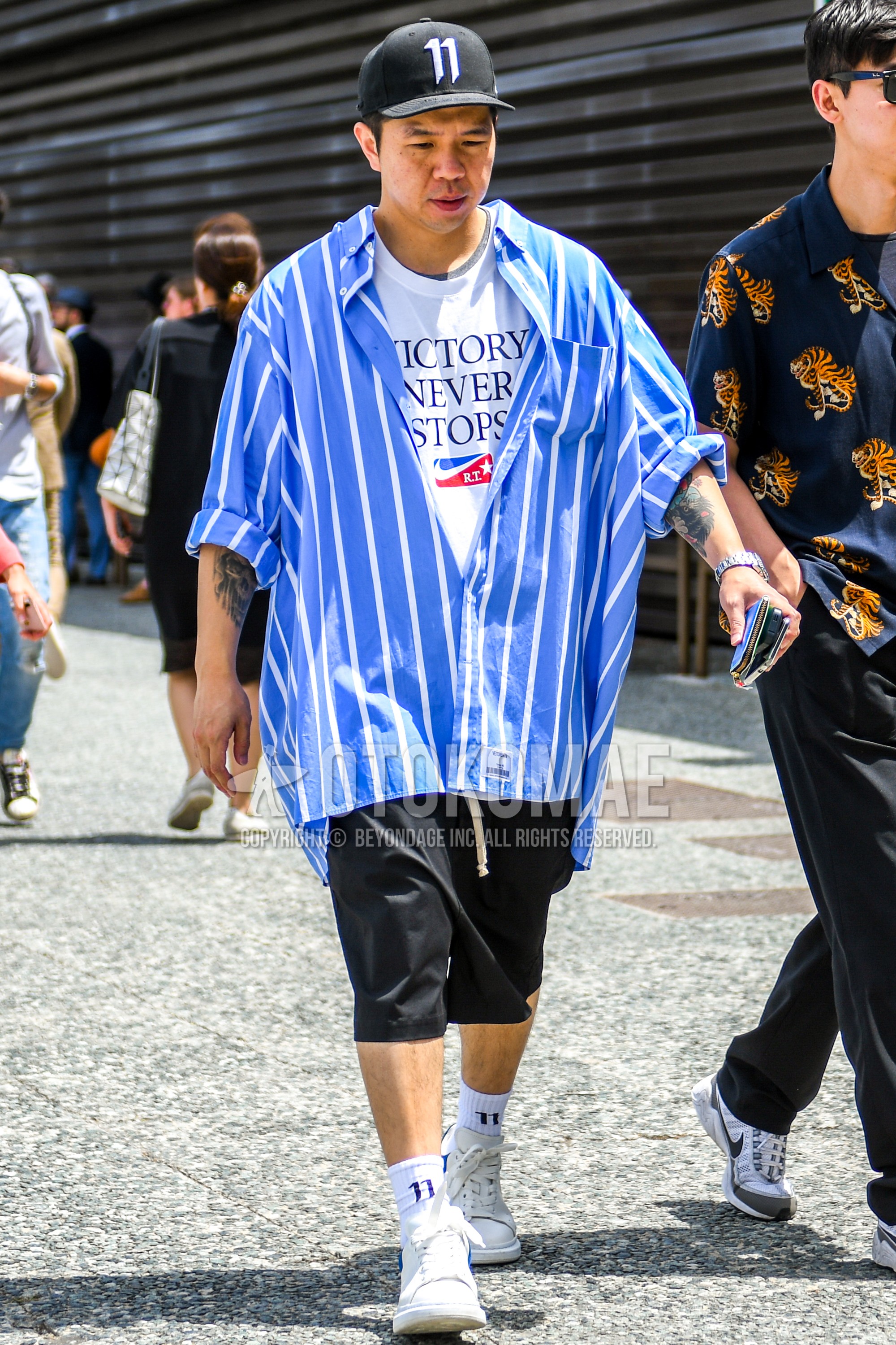 Men's summer outfit with one point baseball cap, light blue white stripes shirt, white graphic t-shirt, black plain short pants, white one point socks, white low-cut sneakers.