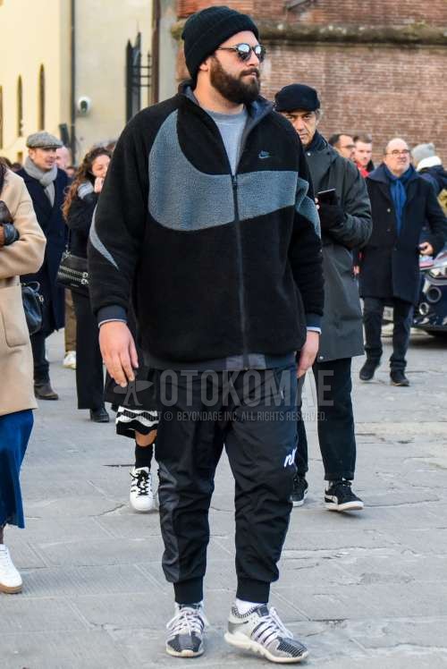 黒無地のニットキャップ、無地のサングラス、黒無地のフリースジャケット、グレー無地のセーター、ナイキの黒無地のジョガーパンツ/リブパンツ、白無地のソックス、アディダスの白ローカットのスニーカーを合わせた冬のメンズコーデ・着こなし。