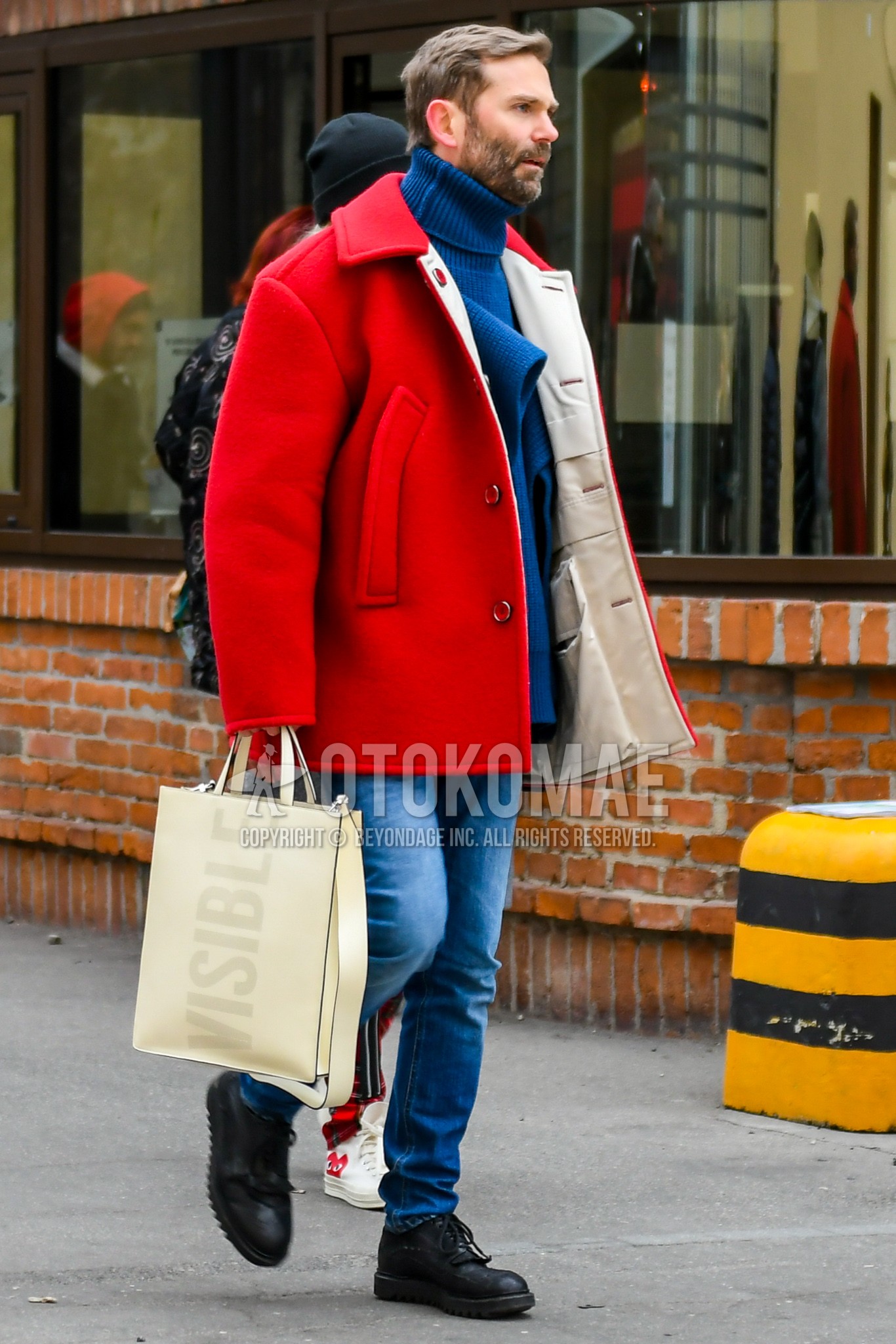 Men's autumn winter outfit with red plain stenkarrer coat, gray plain turtleneck knit, blue plain denim/jeans, black wing-tip shoes leather shoes, beige graphic briefcase/handbag.