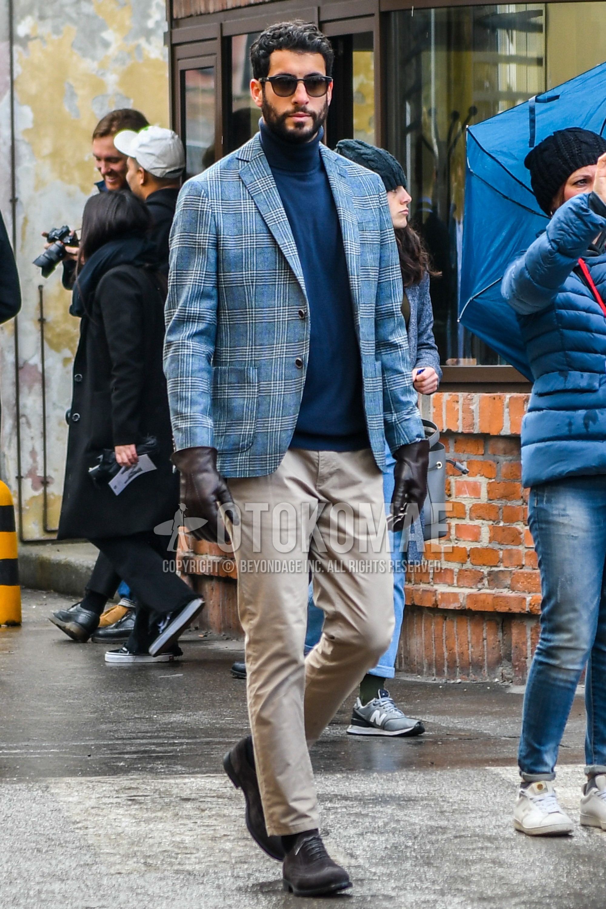 Men's winter outfit with plain sunglasses, blue check tailored jacket, navy plain turtleneck knit, beige plain cotton pants, black socks socks, brown suede shoes leather shoes.