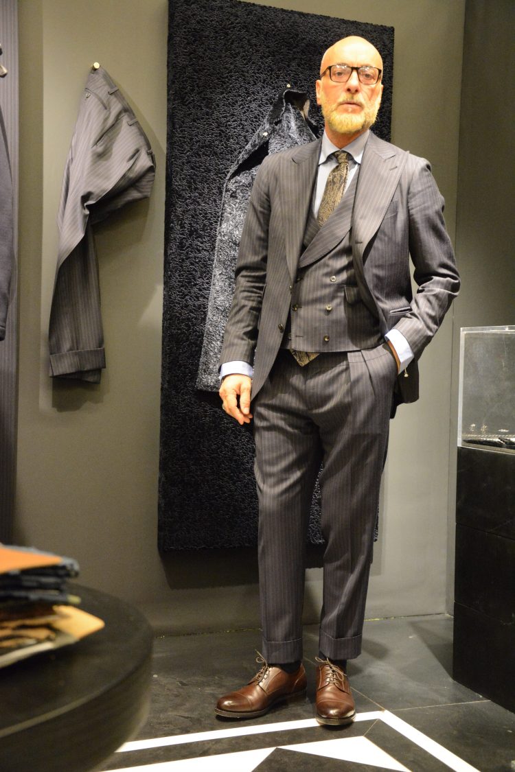 The combination of a wide lapel jacket, pleated pants, and gilet creates a classic three-piece suit style