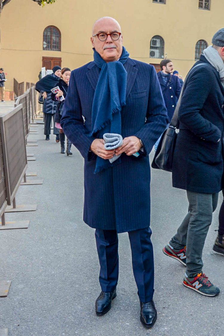 The hanging stole adds an accent to the navy-colored chester coat coordinate.