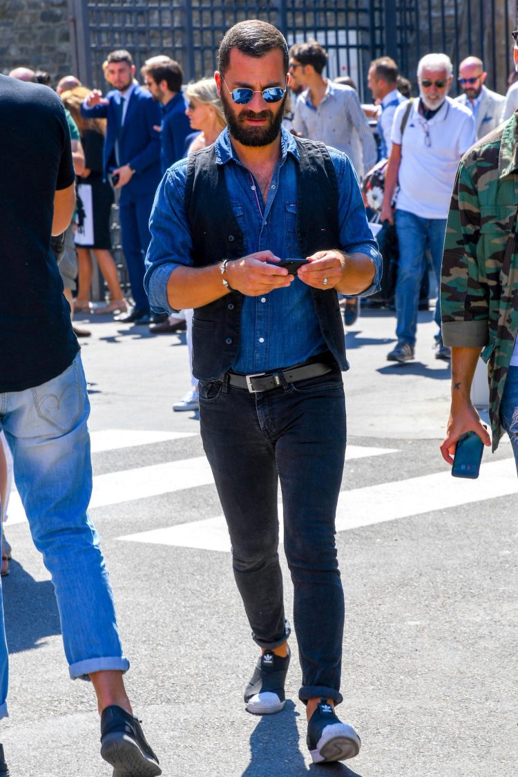 Black denim and a denim shirt combine to create a martial outfit that is tucked in for a classy look.