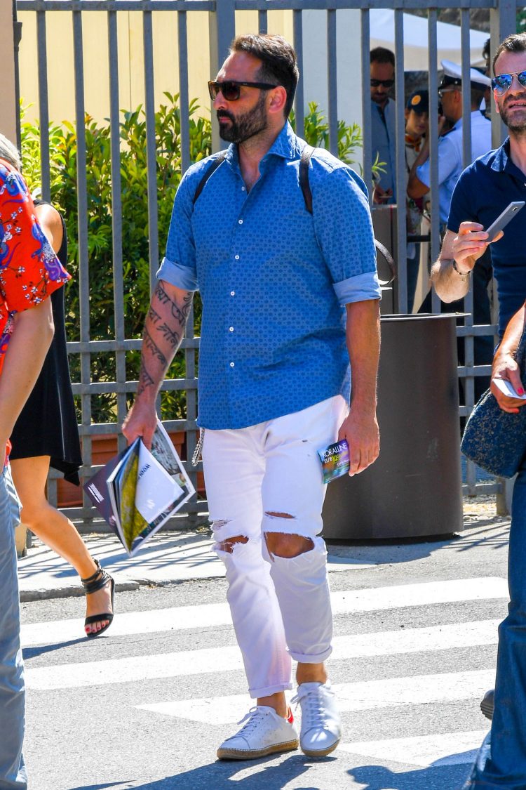 Patterned blue shirt and damaged jeans give a different look to the classic shirt and jeans coordinate.