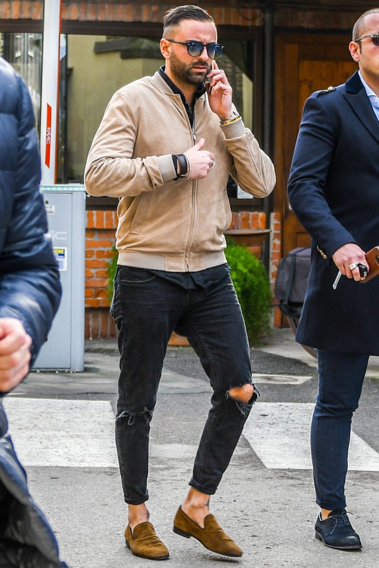 Trend-conscious combination of ripped black denim and brown bomber jacket
