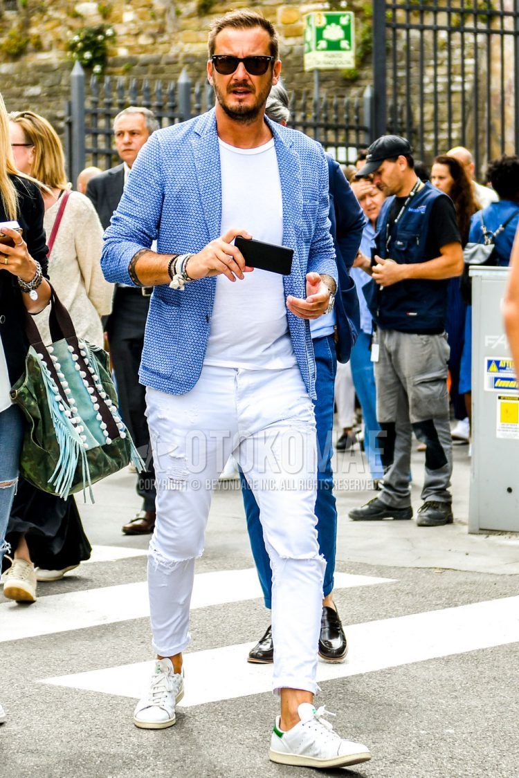 A summer/fall/spring men's coordinate outfit with plain sunglasses, a tailored jacket with blue dots, a plain white t-shirt, plain white damaged jeans, and white low-cut Adidas Stan Smith sneakers.