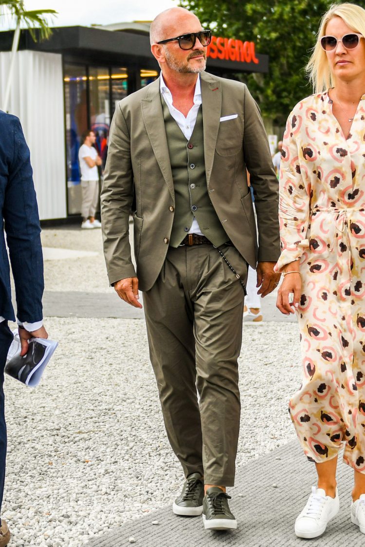 A summer-spring-fall men's coordinate outfit with plain sunglasses, plain white shirt, plain brown mesh belt, plain leather belt, olive green low-cut sneakers, and plain olive green three-piece suit.