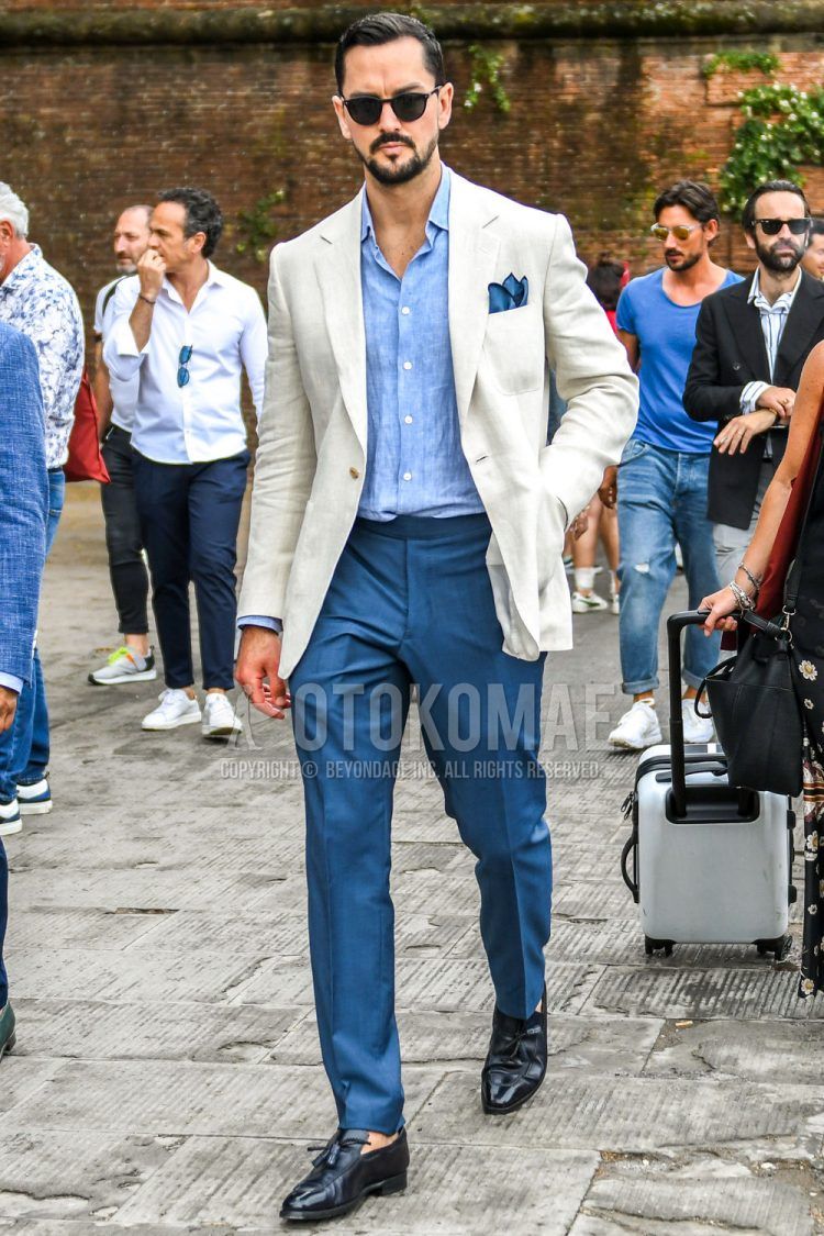 Spring/summer/fall men's coordinate outfit with solid black sunglasses, solid white tailored jacket, solid light blue denim/chambray shirt, solid blue slacks, and black tassel loafer leather shoes.
