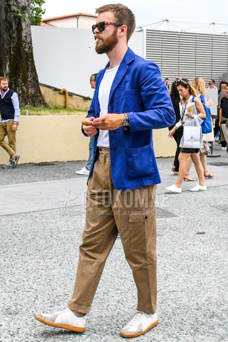 Spring, summer, and fall men's coordinate outfit with plain blue tailored jacket, plain white T-shirt, plain beige cargo pants, and white low-cut sneakers.