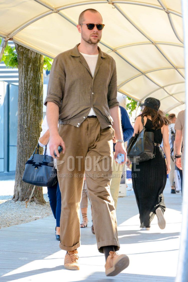 A spring/summer/fall men's coordinate outfit with tortoiseshell sunglasses, plain beige shirt, plain white t-shirt, plain beige chinos, and pink low-cut sneakers.