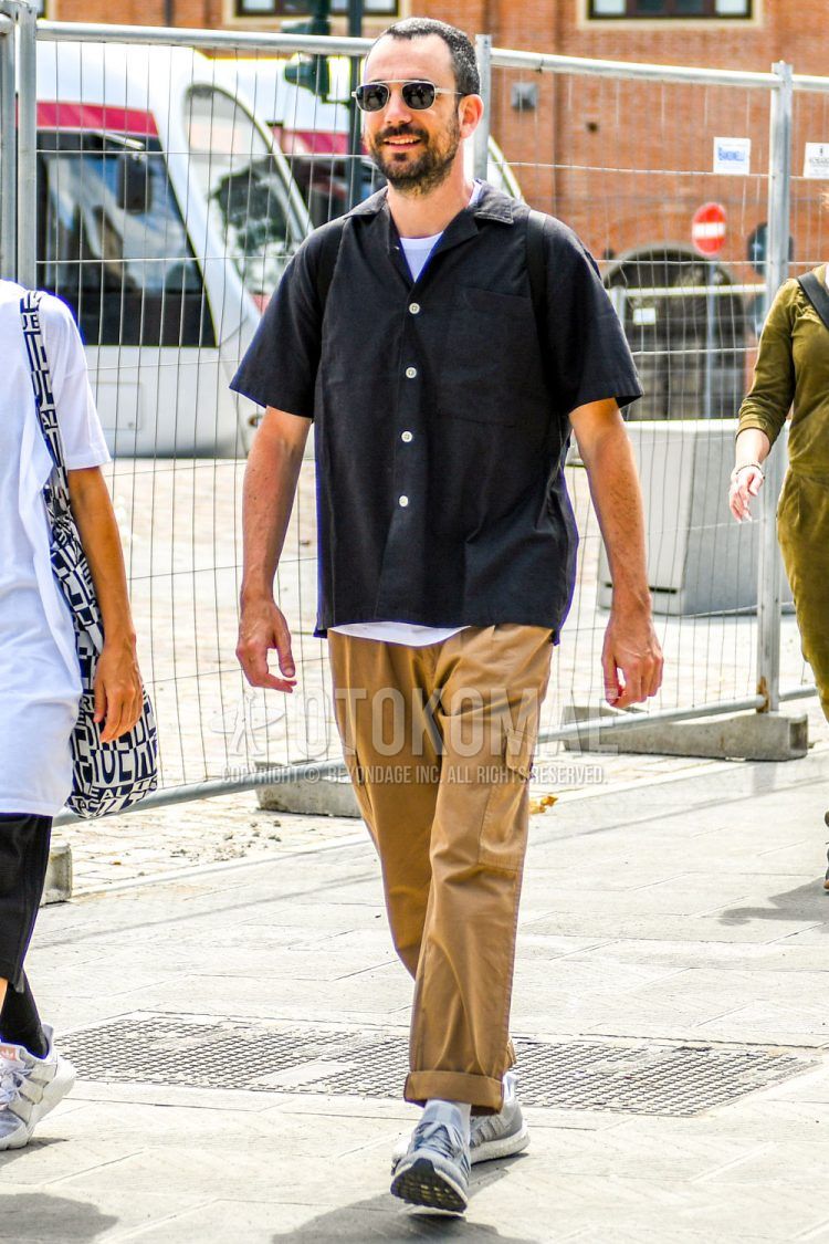 Spring, summer, and fall men's coordinate outfit with plain silver sunglasses, plain black shirt, plain white T-shirt, plain beige cargo pants, and gray low-cut sneakers.