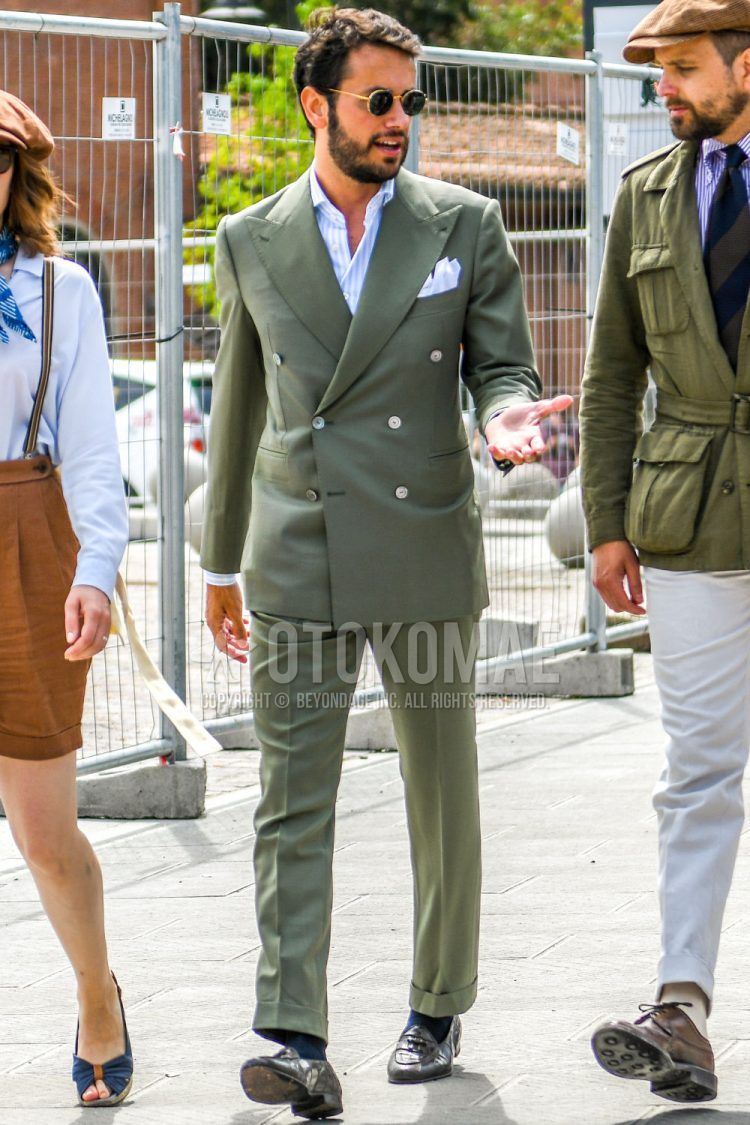 Spring, summer and fall men's coordinate outfit with gold and other sunglasses, light blue striped shirt, solid navy socks, brown tassel loafer leather shoes and solid green suit.