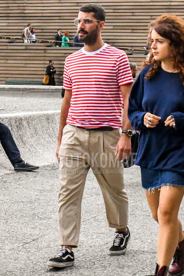 A summer men's coordinate outfit with plain sunglasses, white/red striped t-shirt, plain black leather belt, plain beige ankle pants, plain beige pleated pants, plain beige wide-leg pants, and black sneakers.