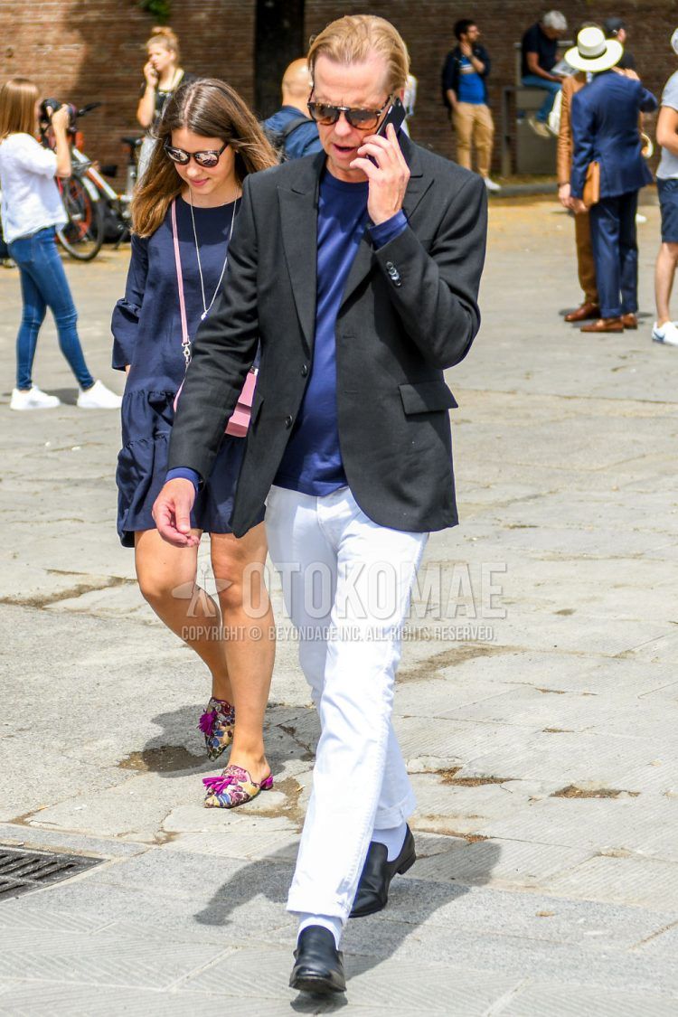 A summer/spring/fall men's coordinate outfit with solid color sunglasses, solid color black tailored jacket, solid color blue t-shirt, solid color white denim/jeans, solid color white cotton pants, solid color white socks, and black other loafer leather shoes.