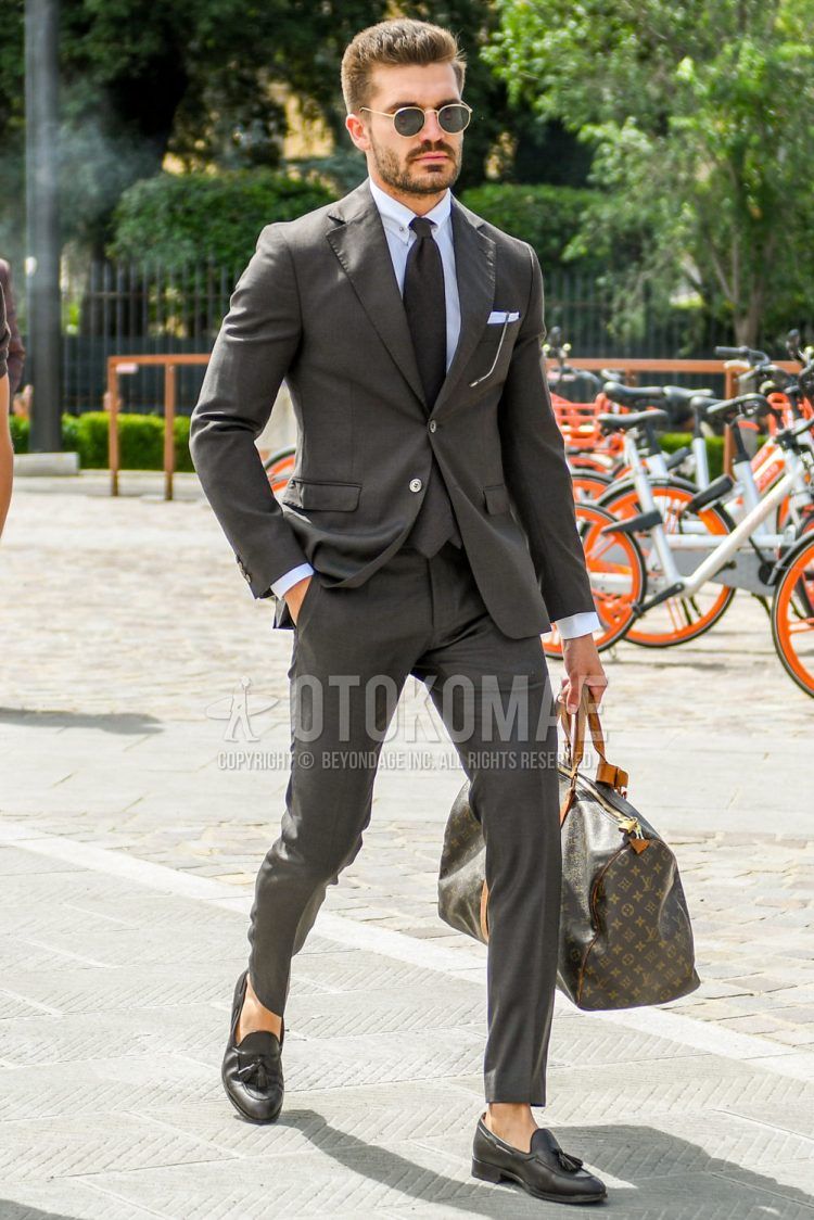 Men's spring/summer/fall outfit with solid color sunglasses, brown tassel loafer leather shoes, Vuitton solid color brown briefcase/handbag, solid color brown suit, solid color brown tie.