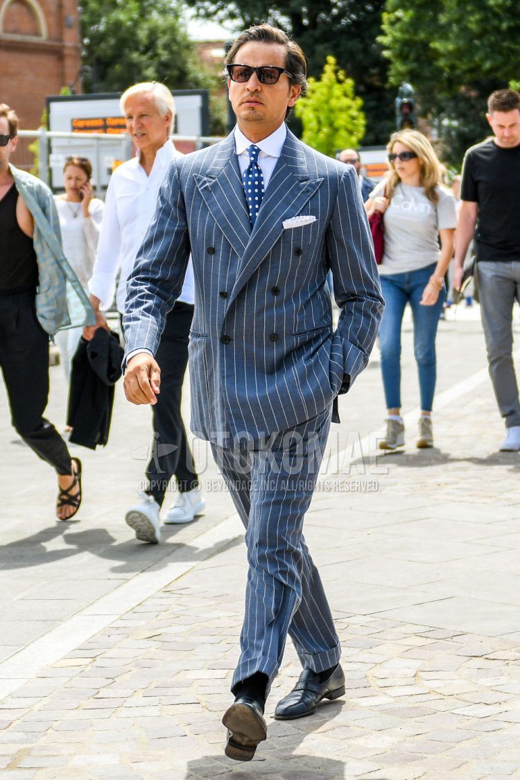 A men's spring/summer/fall outfit with plain sunglasses, plain white shirt, plain black socks, black other loafer leather shoes, gray striped suit, and navy dot tie.