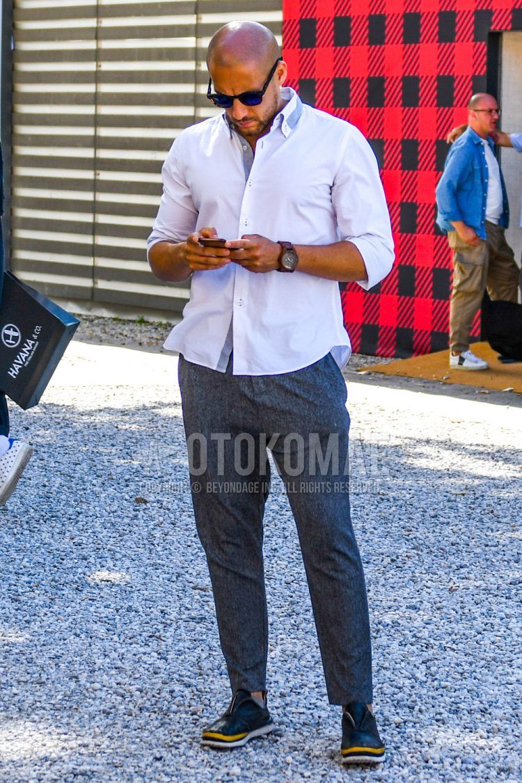 A summer men's coordinate outfit with plain sunglasses, plain white shirt, dark gray plain ankle pants, dark gray plain cotton pants, and black and other leather shoes.