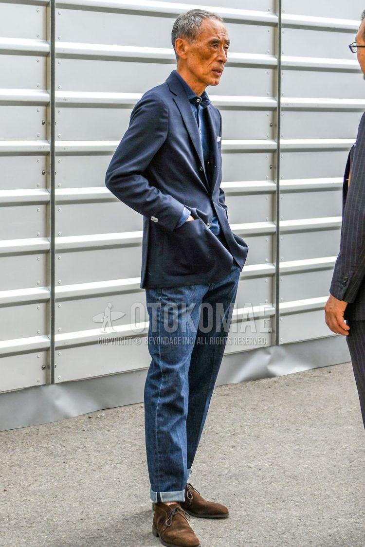 Spring/Summer/Fall men's coordinate outfit with plain navy tailored jacket, plain navy polo shirt, plain blue denim/jeans, and brown chukka boots.