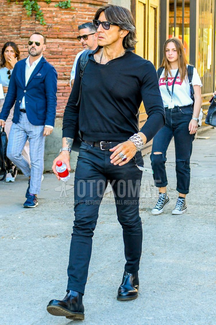 A summer/spring men's coordinate outfit with solid color sunglasses, solid color black polo shirt, solid color black leather belt, solid color black denim/jeans, and black side gore boots.