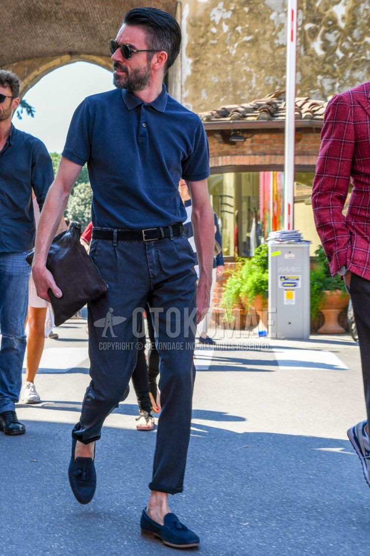 A spring/summer men's coordinate outfit with solid color sunglasses, solid color navy polo shirt, solid color black leather belt, solid color navy cotton pants, and navy tassel loafer leather shoes.