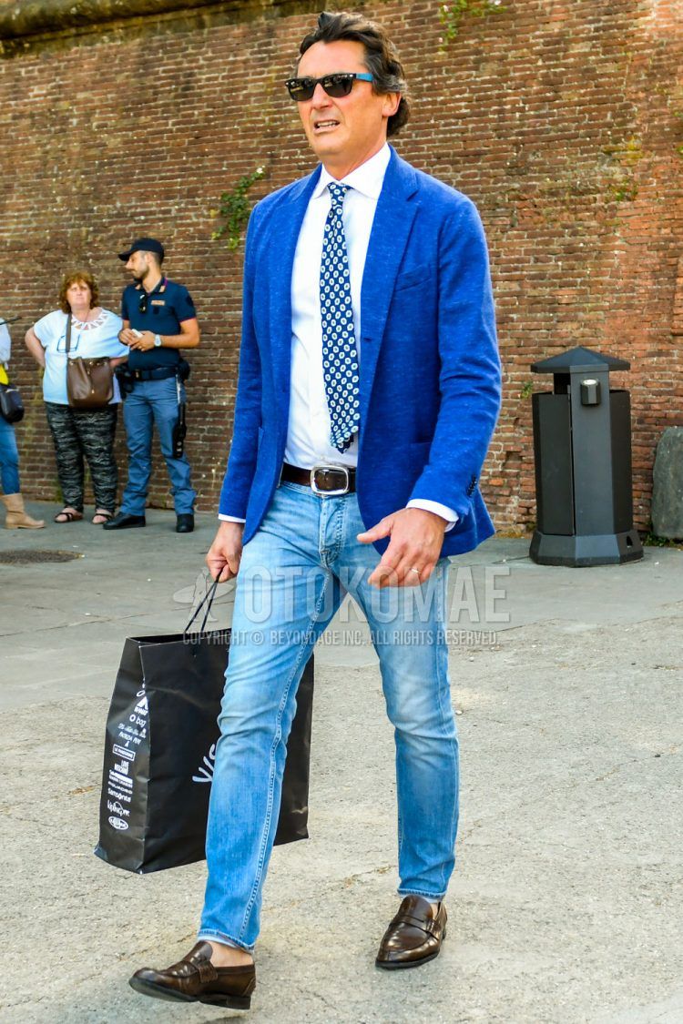 Men's spring/summer/autumn coordinate outfit with solid color sunglasses, solid color blue tailored jacket, solid color white shirt, solid color brown leather belt, solid color denim/jeans, and brown coin loafer leather shoes.