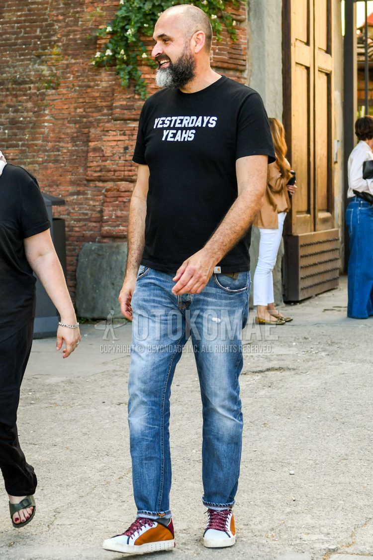 A summer men's coordinate outfit with a black one-pointed T-shirt, plain blue denim/jeans, and white/brown low-cut sneakers.