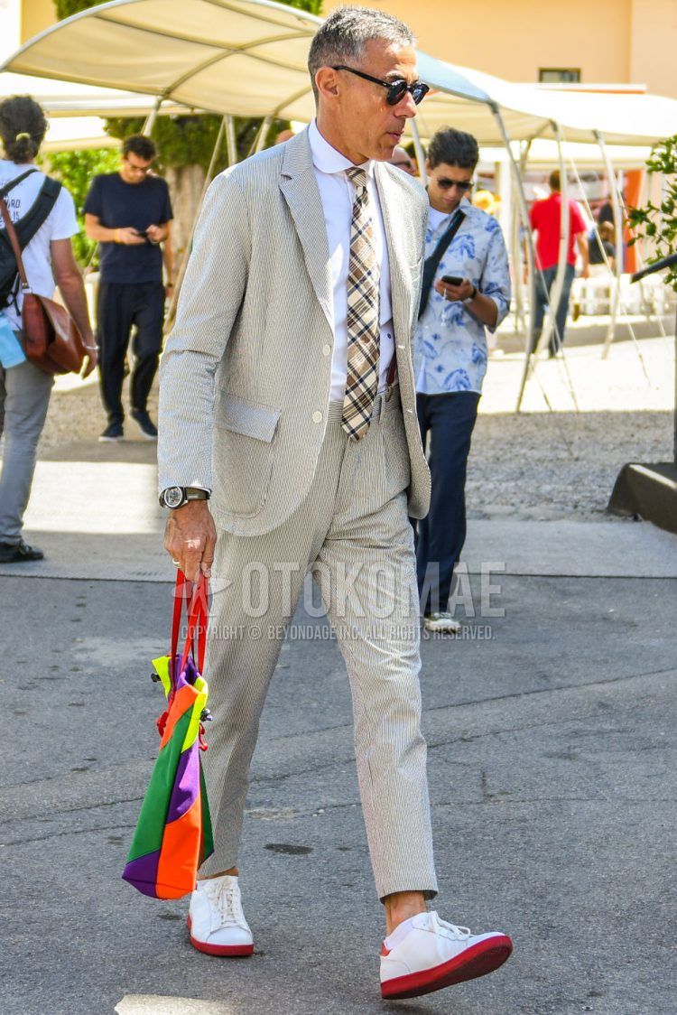Spring, summer and fall men's coordinate outfit with plain sunglasses, plain white shirt, plain suspenders, white low-cut sneakers, beige striped suit and beige checked tie.