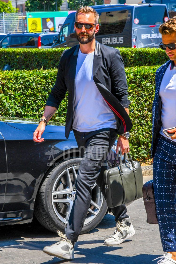A men's spring/summer/fall coordinate outfit with plain sunglasses, a plain black tailored jacket, a plain white T-shirt, plain black easy pants, and white low-cut sneakers.