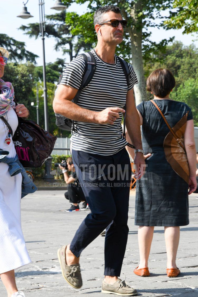 A summer/spring men's coordinate outfit with plain sunglasses, white striped t-shirt, plain navy cotton pants, and beige moccasins/deck shoes leather shoes.
