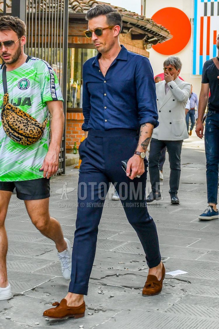 Spring, summer and fall men's coordinate outfit with brown tortoiseshell sunglasses, plain navy shirt, plain navy slacks and brown tassel loafer leather shoes.