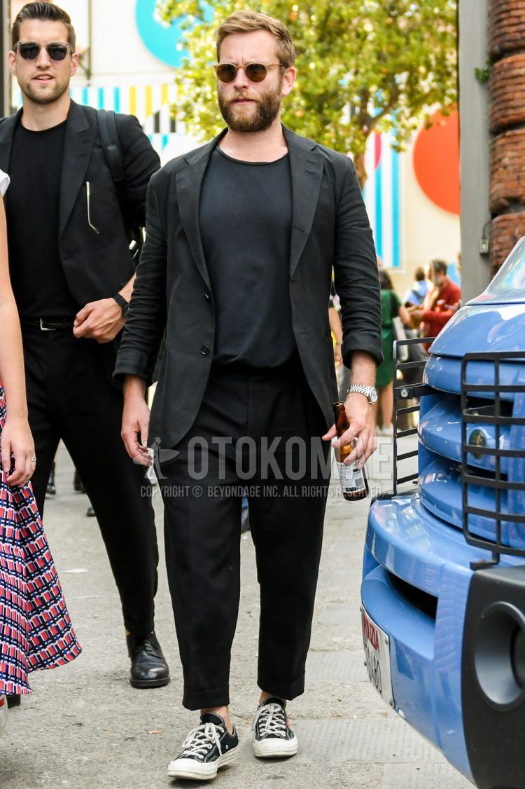 A summer-spring-fall men's coordinate outfit with plain sunglasses, a plain black tailored jacket, a plain black t-shirt, plain black ankle pants, and Comme des Garcons Play Converse Chuck Taylor black low-cut sneakers.