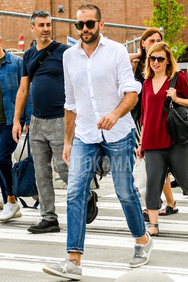A spring/summer men's coordinate outfit with brown tortoiseshell sunglasses, plain white shirt, plain blue denim/jeans, and gray low-cut sneakers.