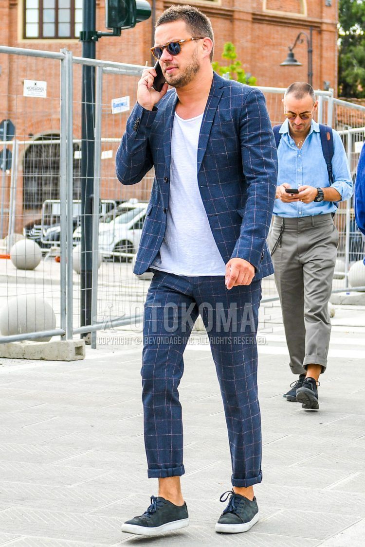 A summer/fall/spring men's coordinate outfit with tortoiseshell sunglasses, plain white t-shirt, navy low-cut sneakers, and navy check suit.