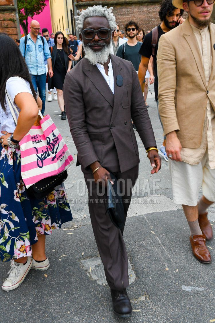 A men's spring/summer/fall outfit for men with plain glasses, plain white shirt, brown plain-toe leather shoes, plain black clutch bag/second bag/drawstring, and plain brown suit.