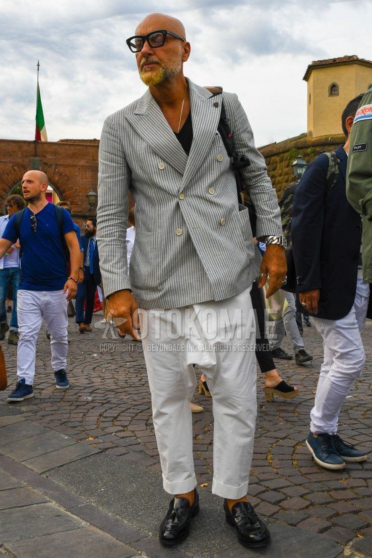 Men's spring, summer, and fall coordinate outfit with plain glasses, white/gray striped tailored jacket, plain black t-shirt, plain white sarouel pants, and black tasseled loafer leather shoes.