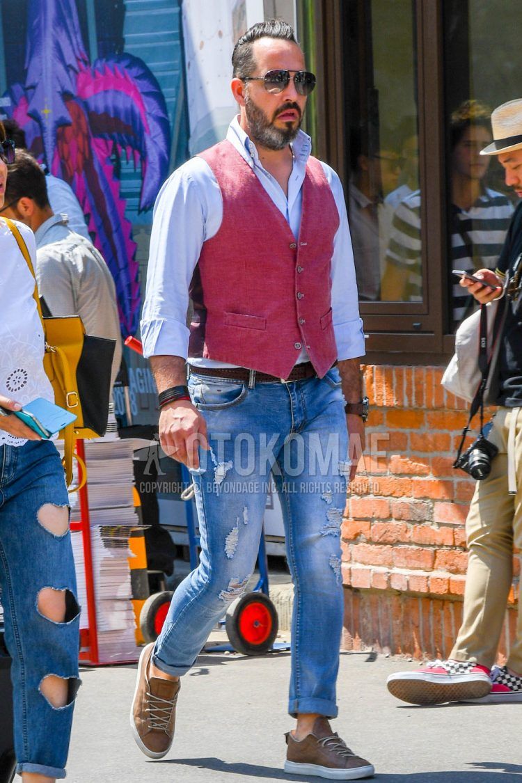 A spring/summer men's coordinate outfit with solid color sunglasses, solid color blue shirt, solid color red gilet, solid color leather belt, solid color blue damaged jeans, and brown low-cut sneakers.