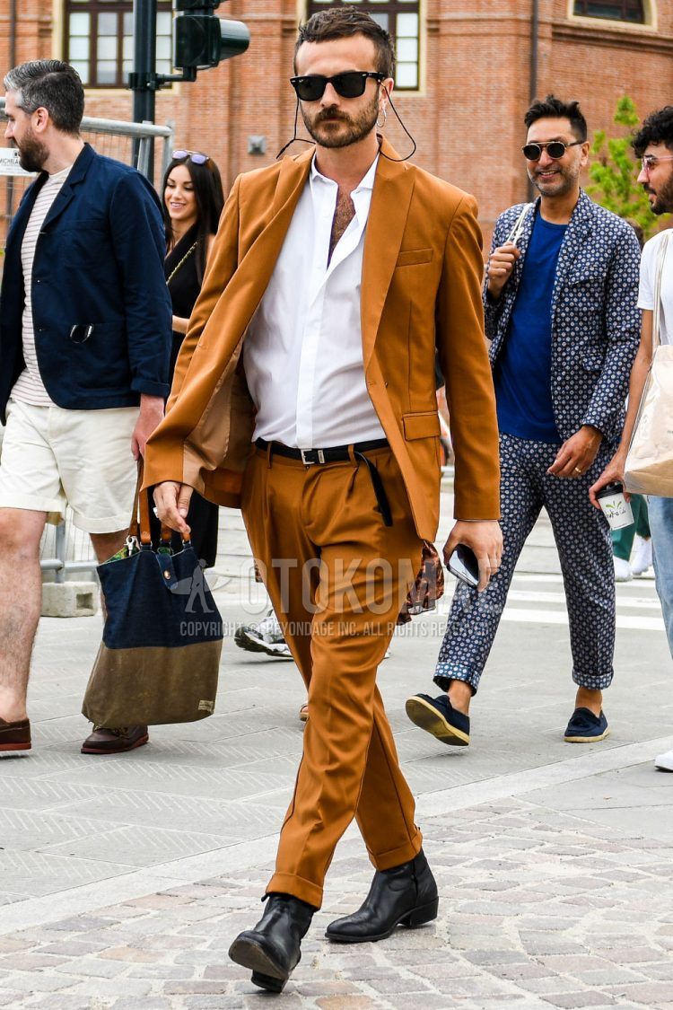 A men's spring, summer, and fall outfit with plain sunglasses, a plain white shirt, a plain black leather belt, black other boots, and a plain brown suit.
