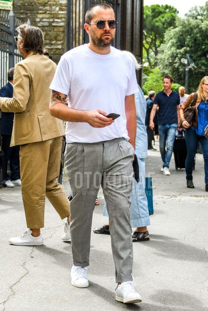 A summer men's coordinate outfit with plain sunglasses, a plain white t-shirt, plain gray slacks, and Adidas Stan Smith white low-cut sneakers.