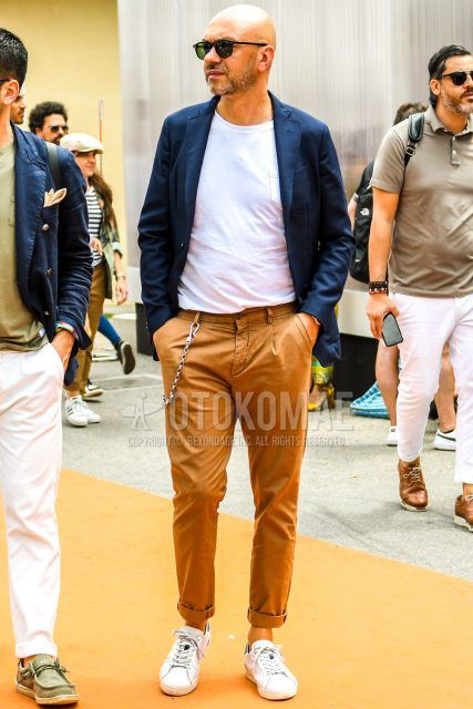 Spring, summer and fall men's coordinate outfit with plain black sunglasses, plain navy tailored jacket, plain white t-shirt, plain brown slacks and white low-cut sneakers.