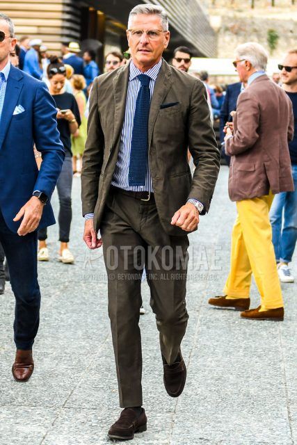 Spring, summer and fall men's coordinate outfit with plain gold glasses, white striped shirt, plain brown leather belt, brown coin loafers leather shoes, brown suede shoes leather shoes, plain brown suit and plain navy knit tie.