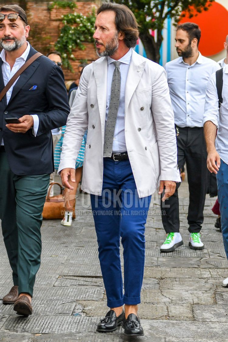 Spring, summer, and fall men's coordinate outfit with plain white tailored jacket, plain white shirt, plain black leather belt, plain blue slacks, black tassel loafer leather shoes, and gray dot knit tie.