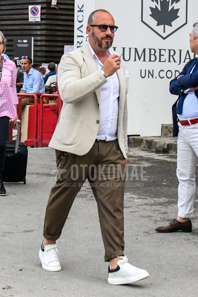 Summer-spring-fall men's coordinate outfit with plain beige tailored jacket, plain white shirt, plain brown pleated pants, plain brown slacks, and white low-cut sneakers.