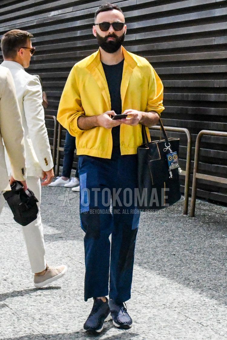 Other solid yellow, solid black t-shirt, solid navy denim/jeans, navy low-cut sneakers, and solid color tote bag for a spring/summer men's outfit.