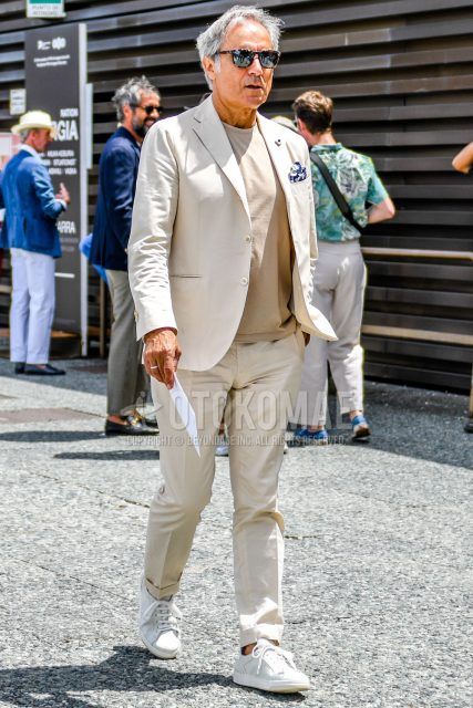 A spring, fall, and summer men's coordinate outfit with tortoiseshell sunglasses, a plain beige T-shirt, white low-cut sneakers, and a plain beige suit.