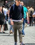 Spring, summer and fall men's coordinate outfit with plain sunglasses, plain navy sweater, plain white t-shirt, plain olive green cotton pants and Adidas navy low-cut sneakers.