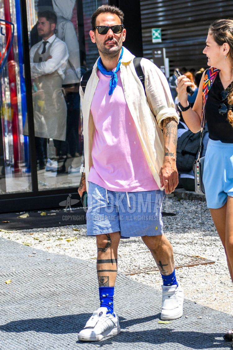 Ray-Ban Wayfarer plain sunglasses, plain white shirt, plain pink t-shirt, blue/white checked shorts, blue and other socks, and white low-cut sneakers for a summer men's outfit.