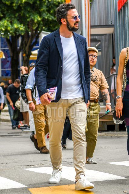 A summer-spring-fall men's coordinate outfit with plain sunglasses, a plain navy tailored jacket, a plain white T-shirt, plain beige chinos, and white low-cut sneakers.
