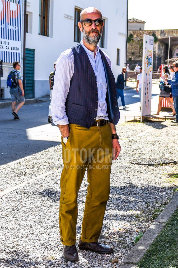 Spring, summer and fall men's coordinate outfit with solid color sunglasses, navy and purple striped gilet, pink and brown striped shirt, solid color brown leather belt, solid color brown wide pants, solid color brown chinos and brown plain toe leather shoes.
