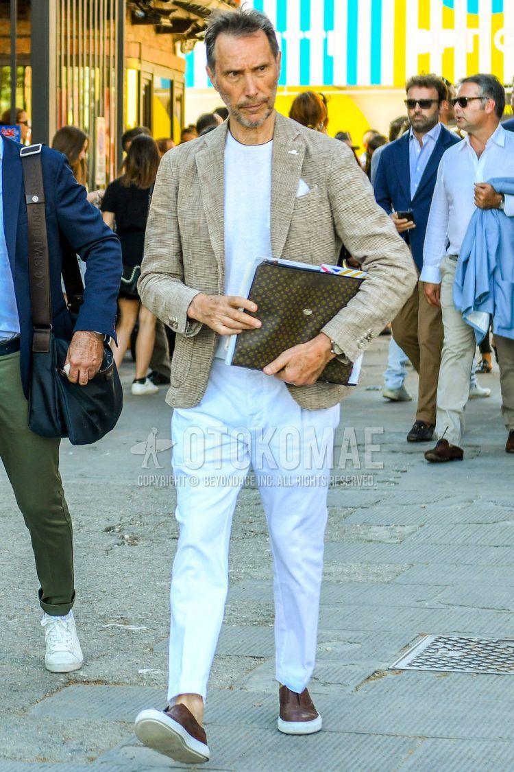 Spring/Summer/Fall men's coordinate outfit with plain beige tailored jacket, plain white sweater, plain white cotton pants, brown slip-on sneakers, brown other clutch bag/second bag/drawstring bag.